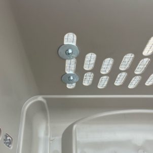 Metal nuts and bolts with flat washers holding the mesh in place